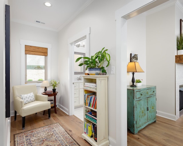 sitting room featuring crown molding, a fireplace, and light hardwood / wood-style flooring