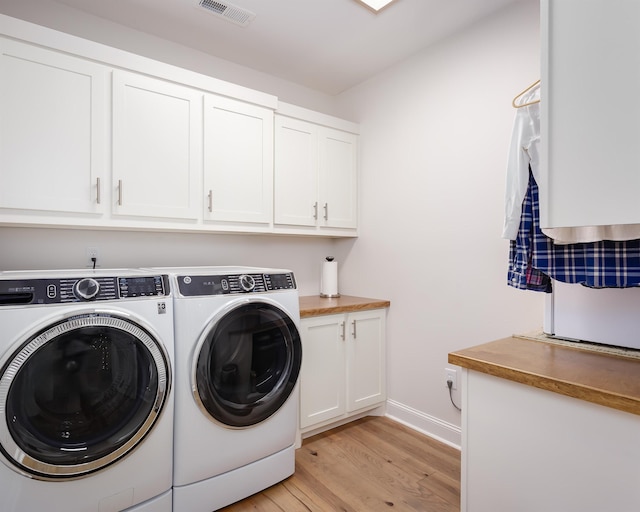 laundry room with cabinets, separate washer and dryer, and light hardwood / wood-style flooring