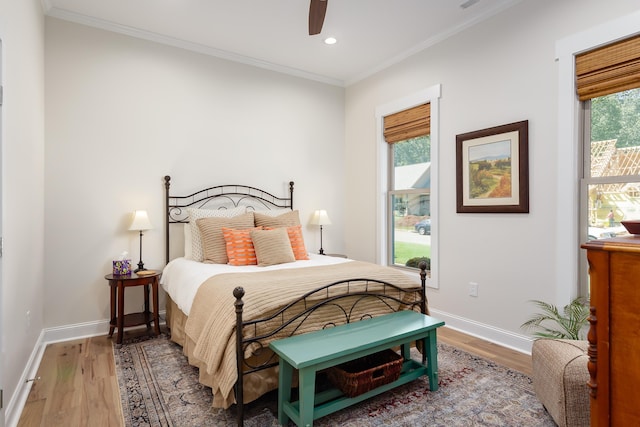 bedroom with hardwood / wood-style flooring, ornamental molding, ceiling fan, and multiple windows