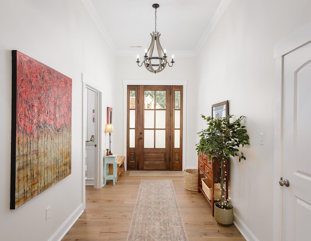 foyer entrance with crown molding, a chandelier, and light wood-type flooring