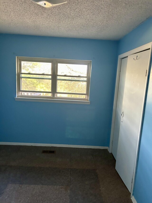 spare room featuring visible vents, a healthy amount of sunlight, a textured ceiling, and baseboards