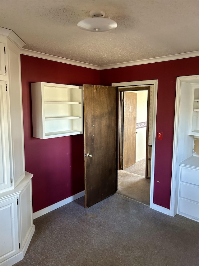 unfurnished bedroom featuring baseboards, a textured ceiling, crown molding, and carpet