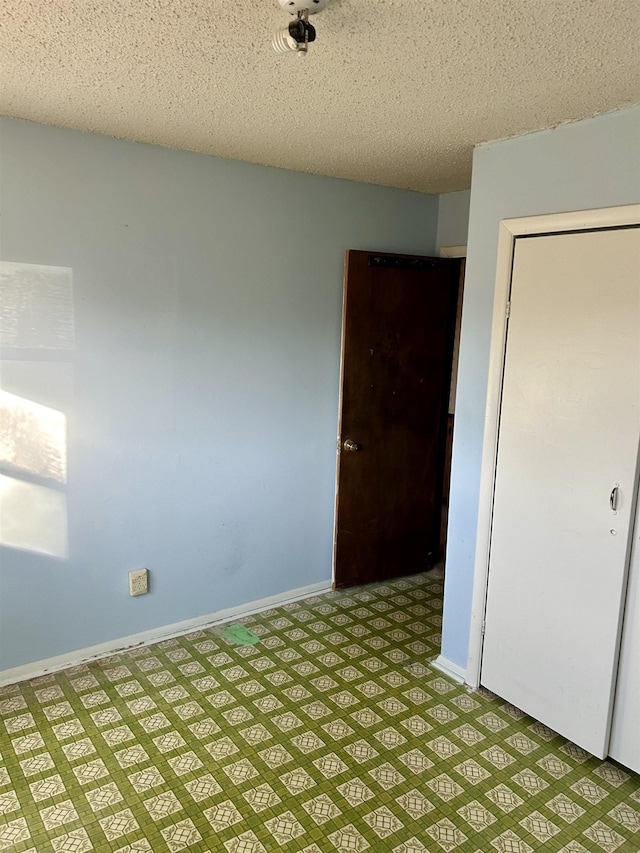 empty room with light floors, baseboards, and a textured ceiling