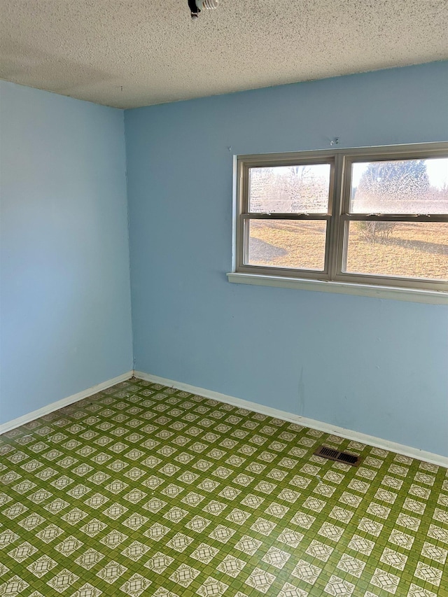 spare room featuring a textured ceiling and baseboards