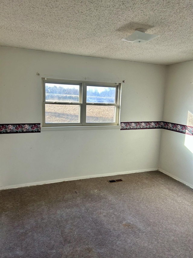 unfurnished room with visible vents, carpet flooring, a textured ceiling, and baseboards