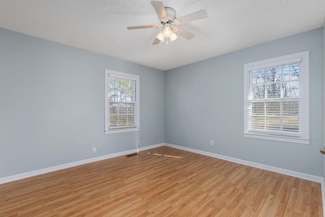 spare room with ceiling fan, a textured ceiling, and light wood-type flooring