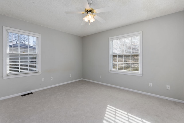 empty room featuring ceiling fan, a healthy amount of sunlight, and a textured ceiling