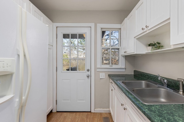 kitchen featuring white refrigerator with ice dispenser, sink, white cabinets, and light hardwood / wood-style floors