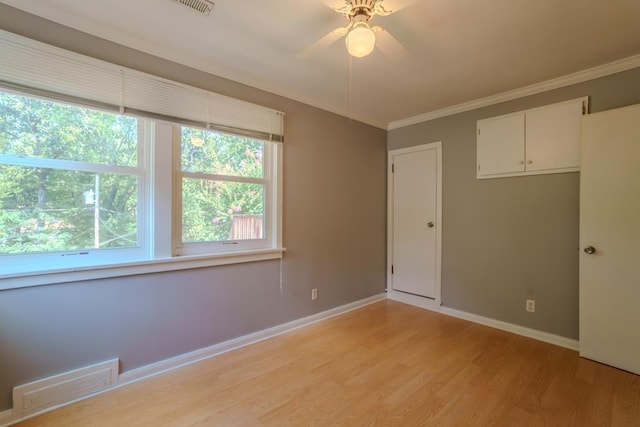 spare room with a wealth of natural light, ceiling fan, light hardwood / wood-style floors, and ornamental molding