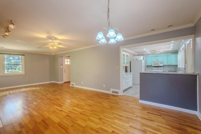 unfurnished living room with rail lighting, ceiling fan with notable chandelier, light wood-type flooring, and ornamental molding