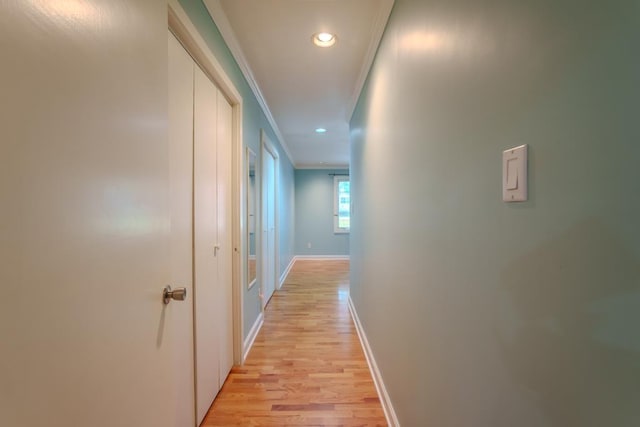 corridor with light hardwood / wood-style floors and crown molding