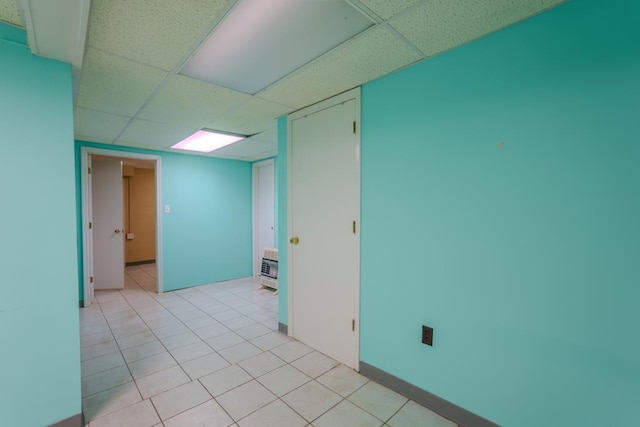 empty room with a drop ceiling and light tile patterned floors