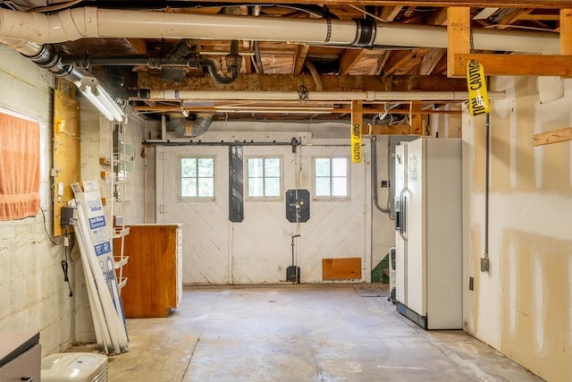 basement featuring white refrigerator with ice dispenser