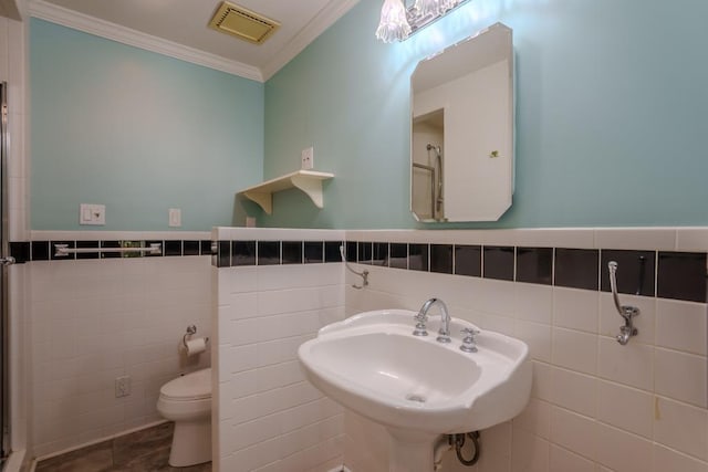 bathroom featuring crown molding, sink, tile patterned flooring, toilet, and tile walls