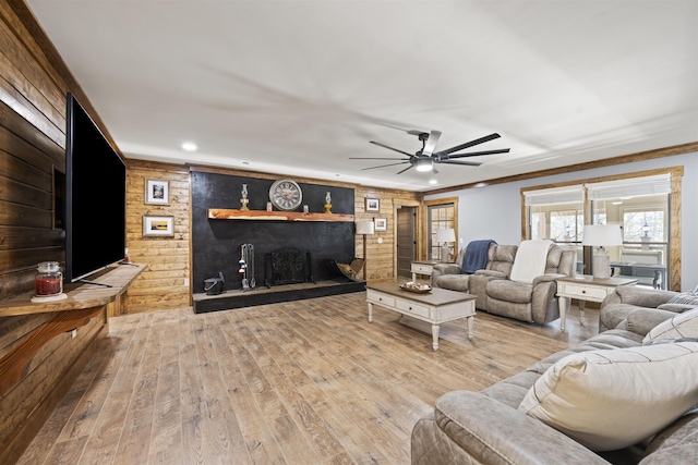 living area featuring wooden walls, a ceiling fan, wood finished floors, recessed lighting, and ornamental molding