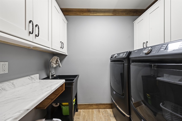 laundry room featuring washer and dryer, baseboards, cabinet space, and light wood-style floors