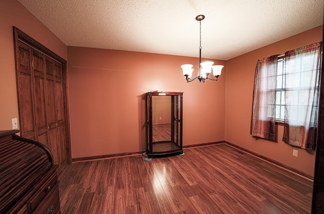 spare room featuring dark hardwood / wood-style flooring, a textured ceiling, and a notable chandelier