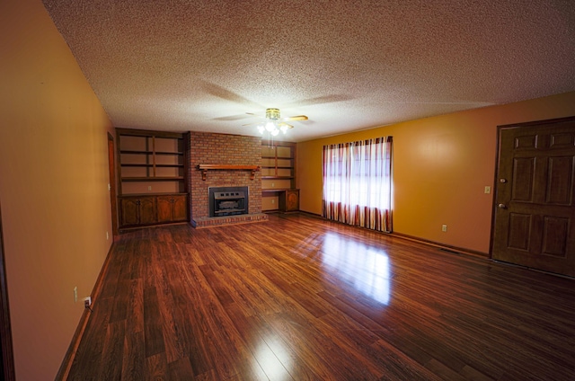 unfurnished living room with built in shelves, ceiling fan, dark wood-type flooring, a textured ceiling, and a fireplace