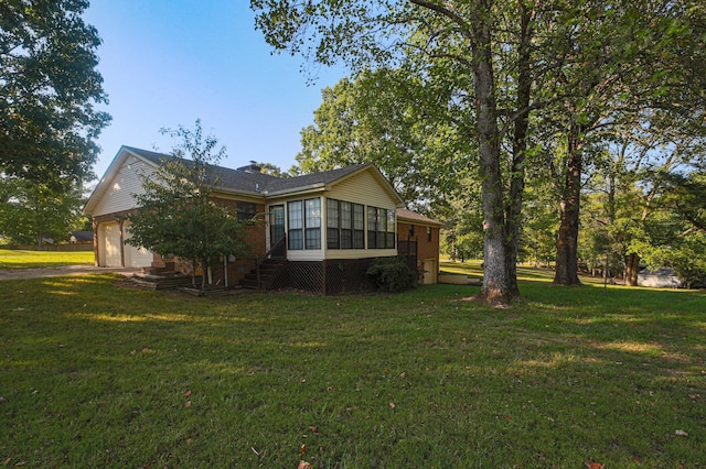 back of property featuring a lawn, a sunroom, and a garage