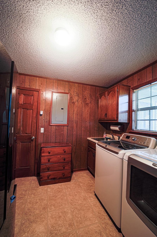 laundry area featuring cabinets, electric panel, sink, wooden walls, and separate washer and dryer