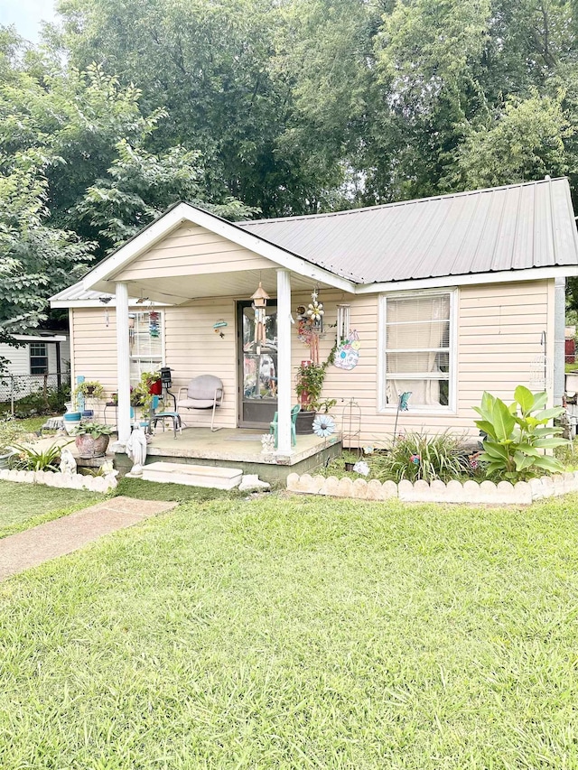  - view of front of house featuring a porch, a front lawn, and a metal roof