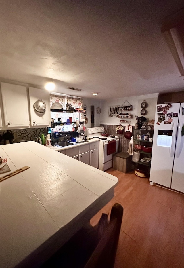  - kitchen with white appliances, white cabinets, and light wood-type flooring