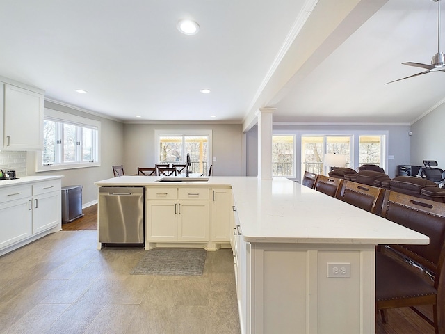 kitchen with crown molding, decorative backsplash, open floor plan, a sink, and dishwasher