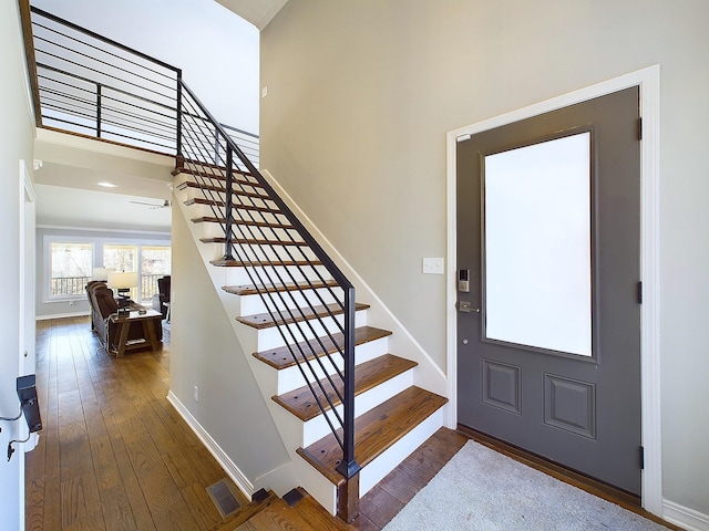 foyer featuring dark wood-type flooring, visible vents, stairway, and baseboards