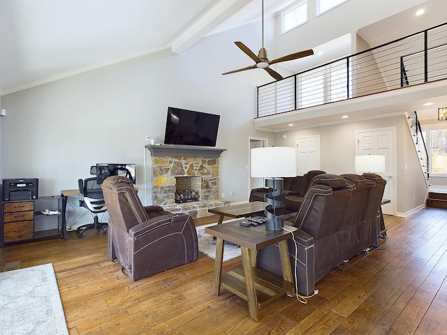 living area featuring high vaulted ceiling, beam ceiling, a stone fireplace, and hardwood / wood-style flooring