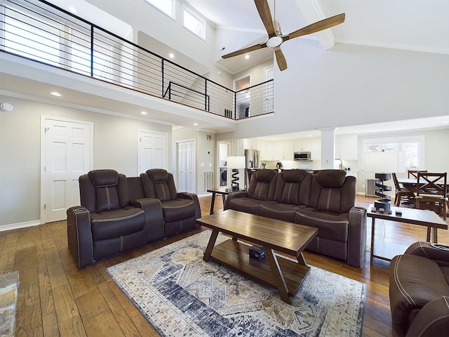 living area featuring decorative columns, baseboards, ceiling fan, hardwood / wood-style floors, and crown molding