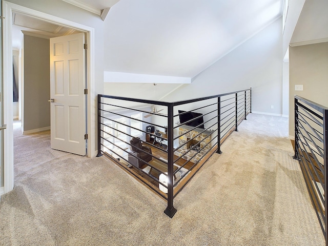 hallway with carpet, baseboards, vaulted ceiling, and an upstairs landing