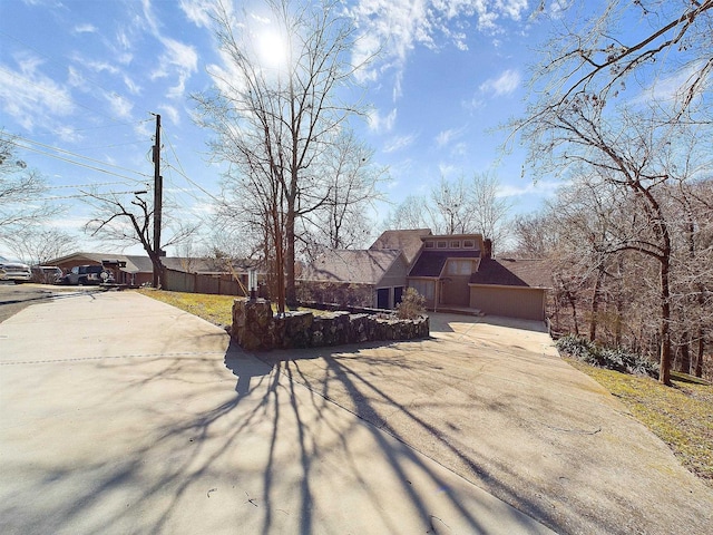 view of front of home with concrete driveway, roof with shingles, and fence