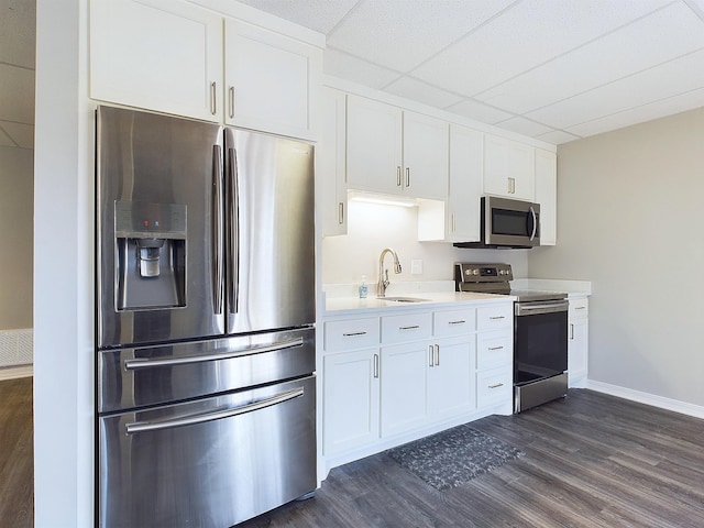 kitchen with white cabinets, dark wood finished floors, stainless steel appliances, light countertops, and a sink