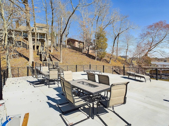 view of patio featuring outdoor dining area, fence, and stairway