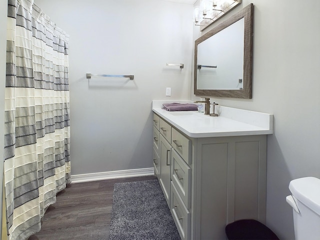 bathroom with baseboards, toilet, a shower with curtain, wood finished floors, and vanity