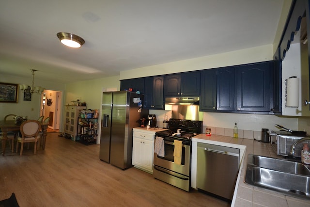 kitchen featuring sink, blue cabinets, tile countertops, a chandelier, and appliances with stainless steel finishes