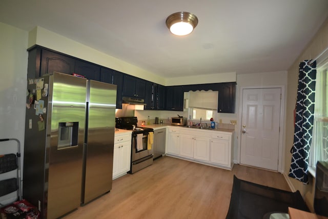 kitchen featuring stainless steel appliances, white cabinetry, light hardwood / wood-style floors, and sink