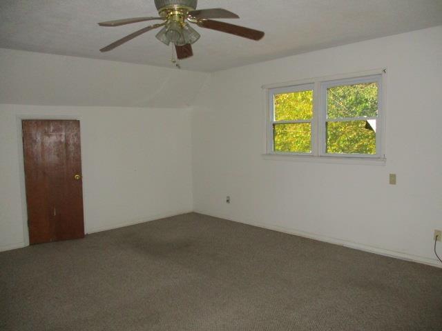 carpeted spare room featuring ceiling fan and lofted ceiling