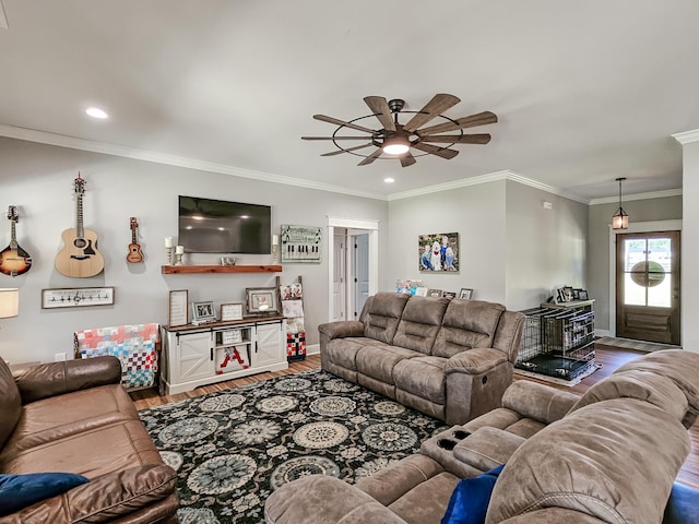 living room with hardwood / wood-style floors, ceiling fan, a wood stove, and ornamental molding