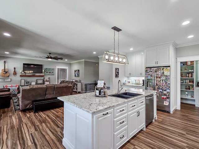 kitchen featuring white cabinets, appliances with stainless steel finishes, hanging light fixtures, and an island with sink