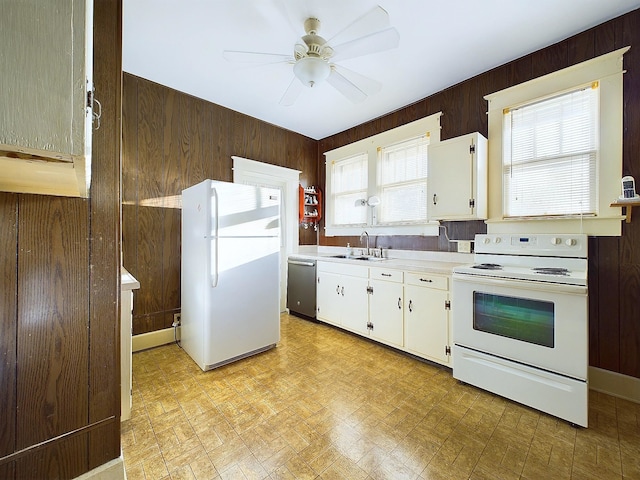 kitchen featuring white cabinetry, sink, wood walls, and white appliances