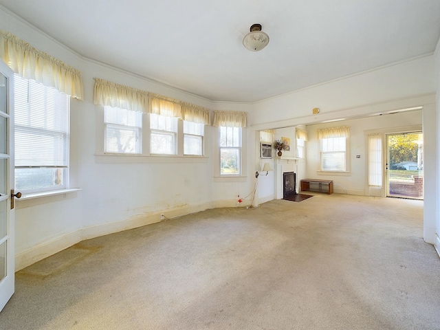 unfurnished living room featuring carpet flooring and ornamental molding