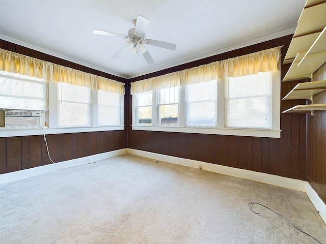 spare room with carpet flooring, wooden walls, ceiling fan, and a wealth of natural light