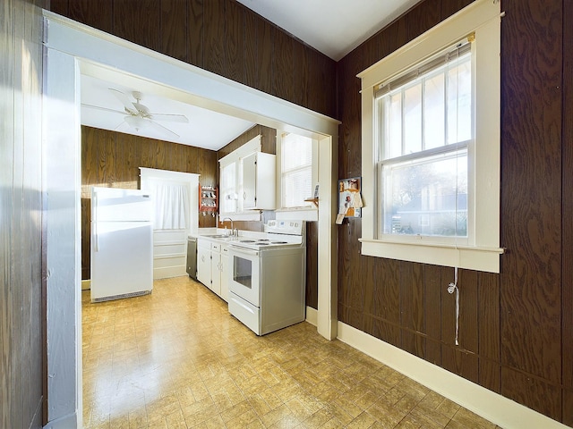 kitchen with ceiling fan, wooden walls, a healthy amount of sunlight, and white appliances