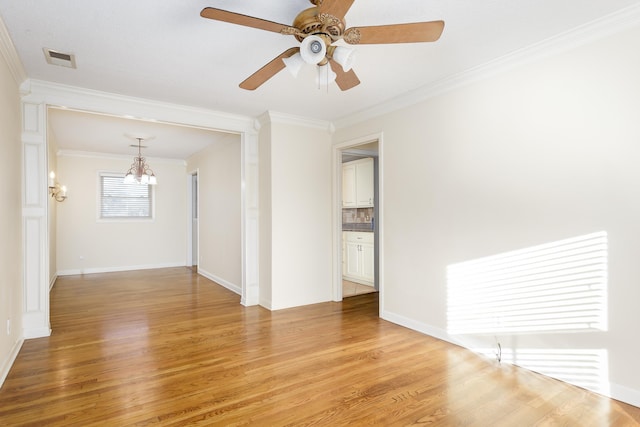 empty room featuring ornamental molding, ceiling fan with notable chandelier, and light wood-type flooring