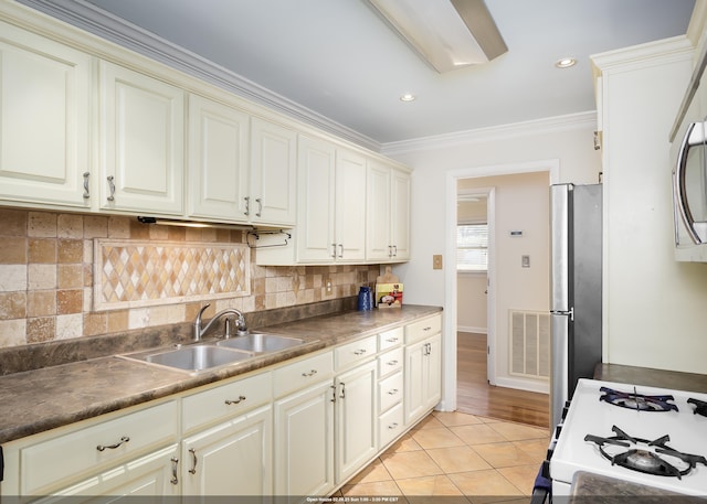 kitchen featuring sink, stainless steel fridge, white range with gas stovetop, ornamental molding, and light tile patterned flooring