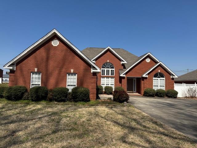 view of front of property with brick siding, a front yard, and fence