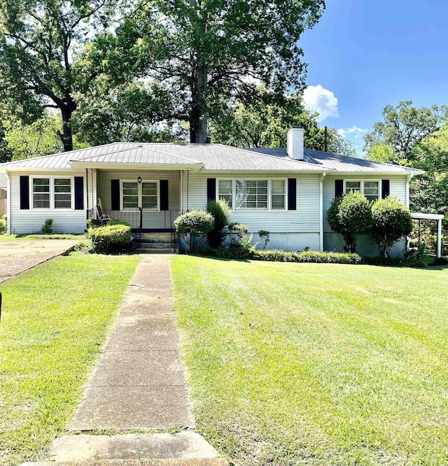  - single story home featuring covered porch, a chimney, a front yard, and a metal roof