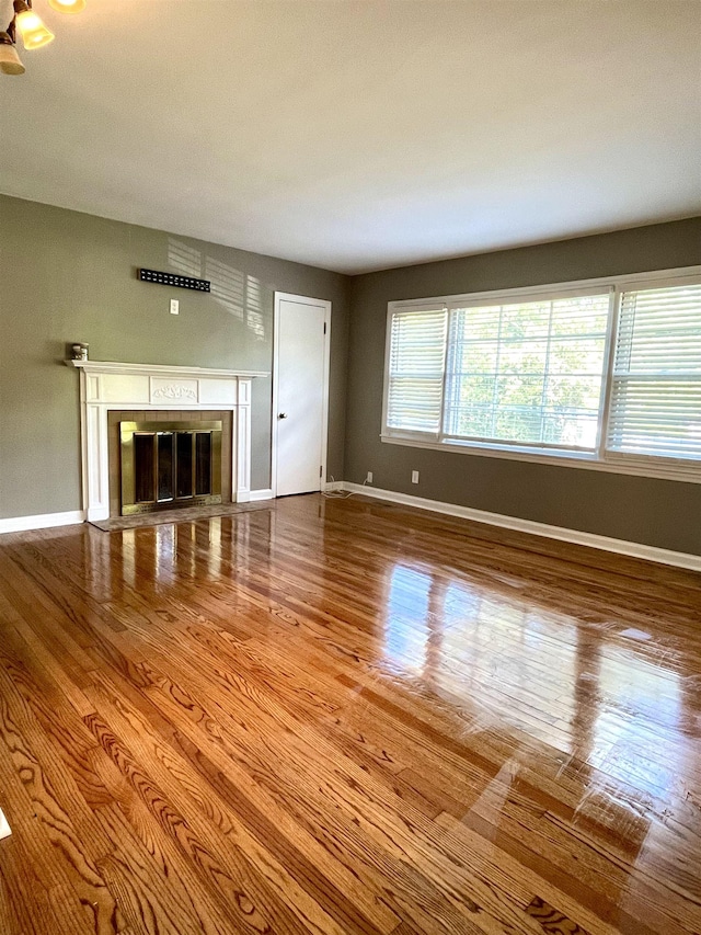  - unfurnished living room featuring wood finished floors and a glass covered fireplace