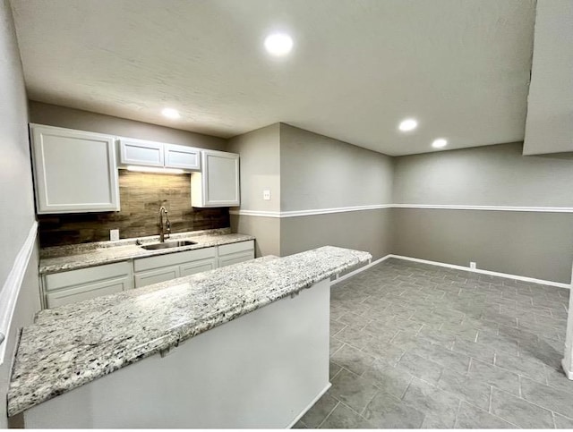  - kitchen featuring light stone countertops, recessed lighting, white cabinetry, and tasteful backsplash